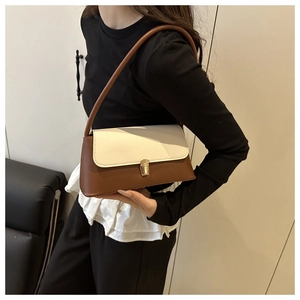 Détail du sac à bandoulière contrasté avec boucle dorée et bandoulière marron