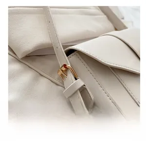 Detailed close-up of golden metal adjustment buckle on off-white leather shoulder strap