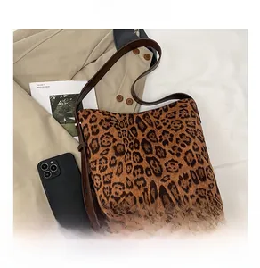Close-up of leopard print texture and dark brown leather strap on large shoulder bag
