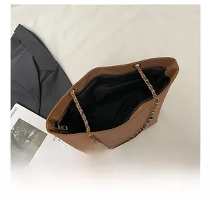 Detail view of the spacious interior with black lining and gold chain strap of the tote bag