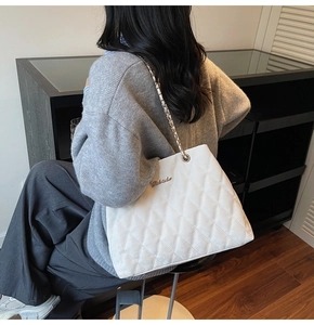 Rear view of model wearing a white quilted chain shoulder bag for daily office style