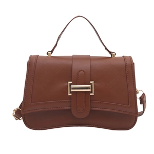 Quilted caramel brown crossbody bag with gold buckle and top handle on white background