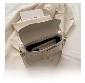 Internal view showing storage capacity of a beige leather crossbody bag with smartphone