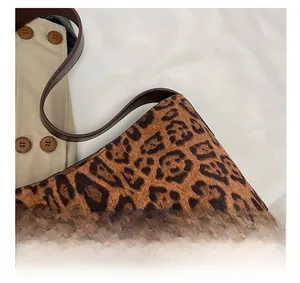 Detail shot of leopard print tote bag with brown leather strap and vintage button closure