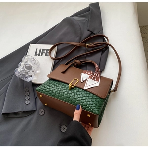 Detail of green woven leather bag with brown flap, gold U-buckle and floral silk scarf