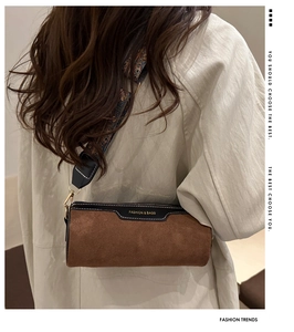Close-up of brown suede barrel bag with stylish ethnic print wide fabric strap