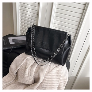 Détail du sac bandoulière en cuir froissé noir avec chaîne argentée et fini mat