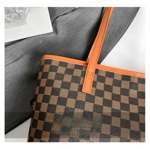Close-up of classic checkered pattern tote bag with orange leather stitching details