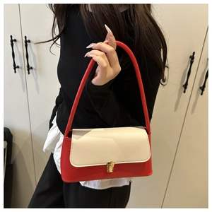 Détail du sac sous le bras bicolore rouge et crème avec fermoir rotatif doré poli