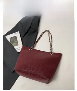 Detail of burgundy leopard print leather tote bag with gold chain strap and stylish texture