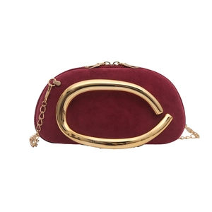 Burgundy suede chain shoulder bag with a large gold C-shaped metal buckle and zipper