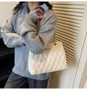 Detail of white quilted leather texture and metallic chain strap on shoulder bag
