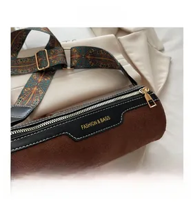 Detailed view of brown suede cylinder bag with bohemian print strap and gold zipper