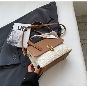 Close-up of woven leather handbag with gold metal clasp and floral scarf wrapped on handle