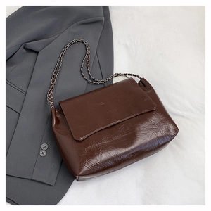 Détail du cuir verni marron froissé et de la chaîne argentée sur un sac à main