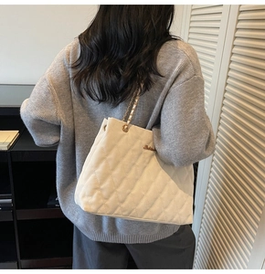 Detailed back view of white quilted shoulder bag with golden chain and metal logo