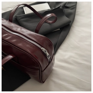Detailed macro shot of burgundy faux leather texture and silver zipper of tote bag