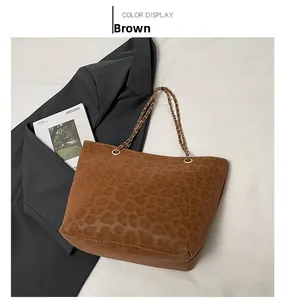 Close-up of brown leopard print tote bag with gold chain strap on grey blazer