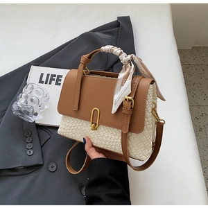 Detail of a vintage-style brown leather bag with woven panels and decorative silk scarf