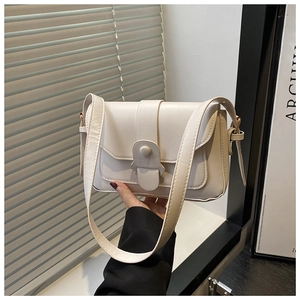 Detail of minimalist beige flap bag with unique wide strap and metal buckle closure