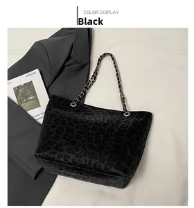 Detail of black leopard print tote bag with gold chain strap on grey blazer background