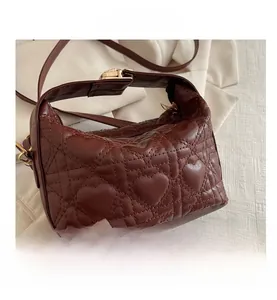 Detail view of heart-shaped quilting and golden twist lock on the dark brown handbag