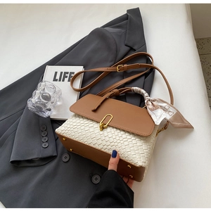 Detail of a brown leather and woven handbag with gold U-buckle and floral silk scarf handle