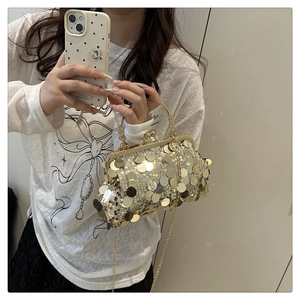 Close-up of golden sequin evening bag featuring a metal handle and elegant chain strap