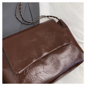 Gros plan d'un sac bandoulière en similicuir marron foncé avec chaîne argentée