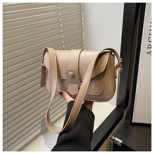 Detail view of beige minimalist handbag with matte leather texture and button closure