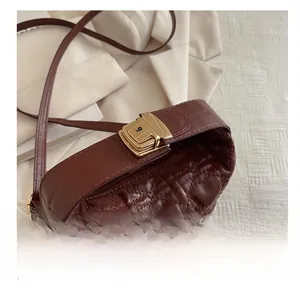 Close-up of a brown quilted crossbody bag with heart pattern and gold hardware