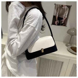 Detail of minimalist black and white leather shoulder bag with gold clasp and sleek strap