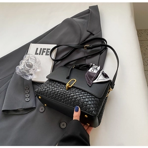 Detail of black woven handbag with silk scarf, gold buckle on grey suit jacket