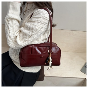Detail of burgundy PU leather Boston bag with beaded pendant and snap front pocket