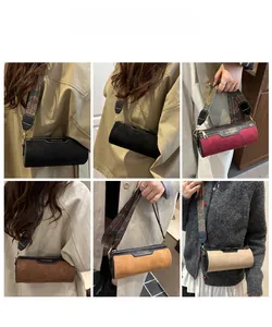 Detail view of suede cylinder crossbody bags with vintage embroidered wide straps in multi colors