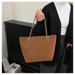 Detail of leopard print tote bag with gold chain strap shown on model for daily commute