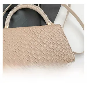 Detail shot of beige handbag showing croc-embossed texture and gold-tone metal hardware