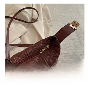 Detailed macro view of the smooth golden metal zipper on a brown quilted bucket bag