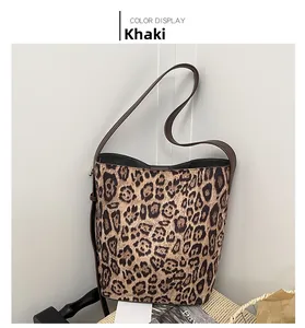 Detail view of khaki leopard print bucket bag with adjustable brown strap on a chair