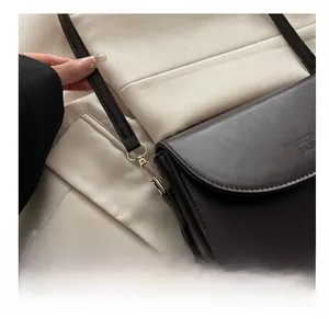 Detail of dark brown leather handbag with gold metal hook and adjustable strap