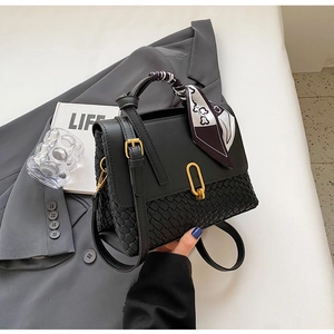 Detail of black woven leather handbag with gold U-buckle and decorative silk scarf