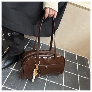 Detail of dark brown glossy pillow bag with stylish wooden bead charm accessory
