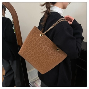 Detail of leopard print tote bag with golden metal chain strap and soft suede texture