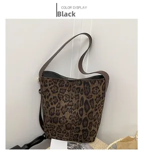 Detailed view of leopard print bucket bag with brown strap and dark interior lining