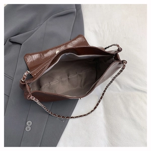 Détail de la doublure intérieure spacieuse et de la bandoulière chaîne d'un sac marron