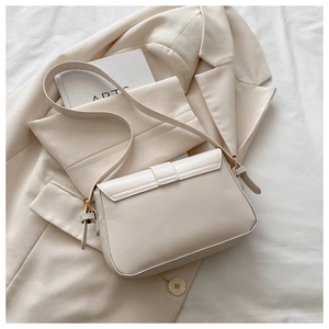 Sac bandoulière minimaliste en cuir crème avec bandoulière réglable sur fond blanc épuré