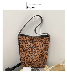 Brown leopard print bucket bag displayed on a woven stool with lifestyle props