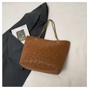 Détail du sac cabas léopard avec bandoulière chaîne sur fond de blazer gris foncé