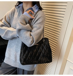 Detail of black quilted chain shoulder bag featuring classic diamond pattern and metallic strap