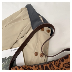 Close-up of leopard print tote bag texture with brown leather strap on a trench coat